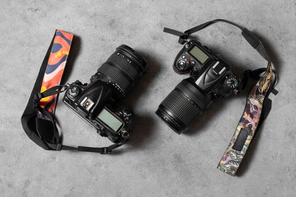 Two SLR cameras in a flat lay with colorful camera straps attached.